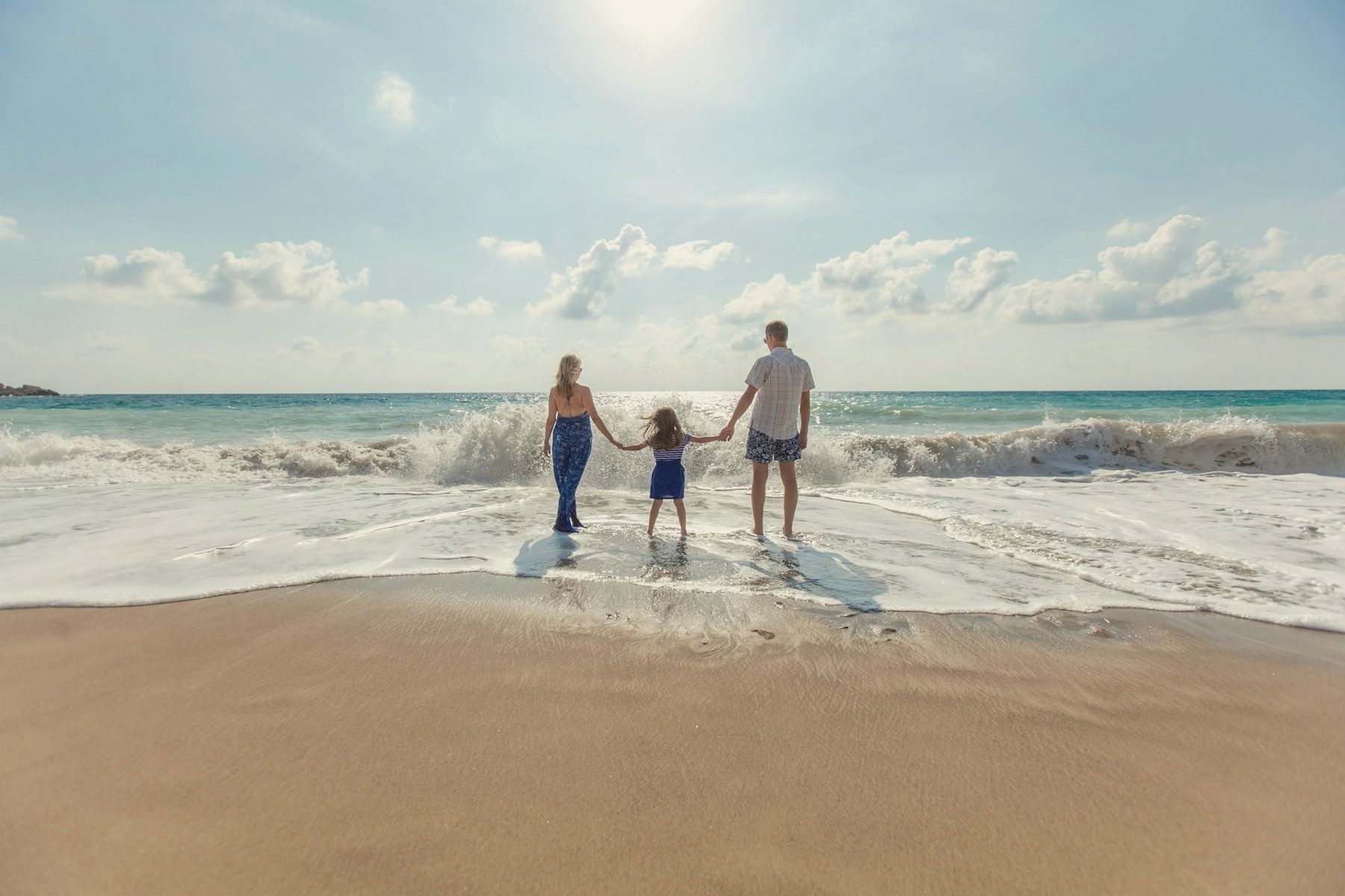 A family walking hand in hand at the edge of the sea
