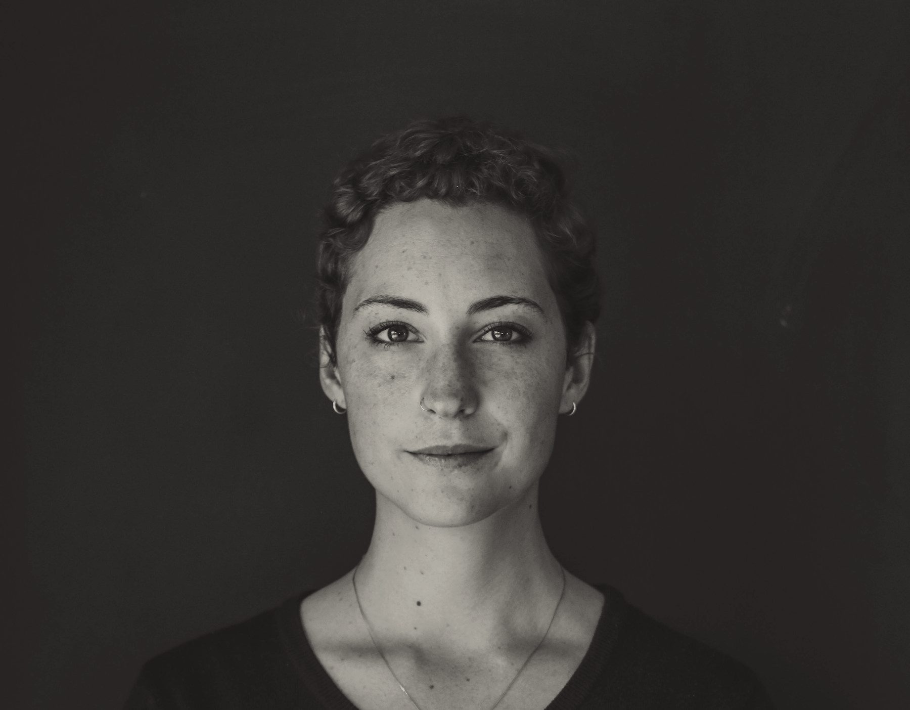 A black-and-white portrait of a woman with short curled hair