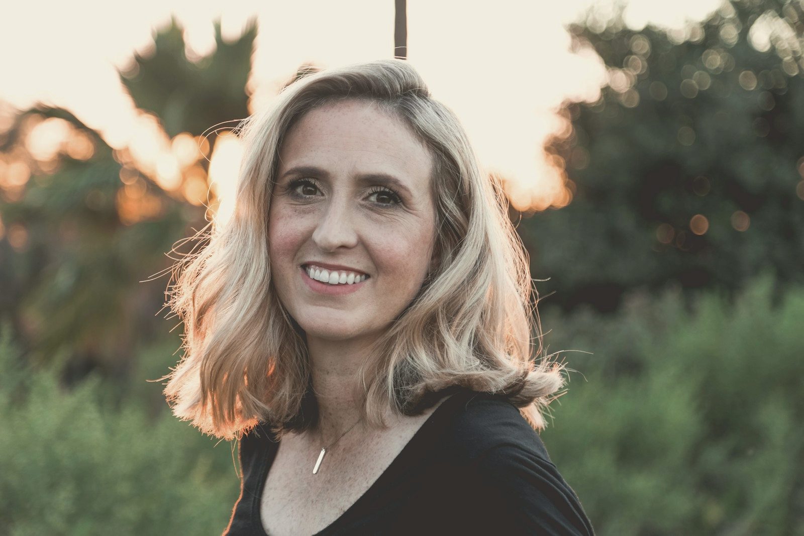 A woman with grey hair, smiling, in late afternoon light