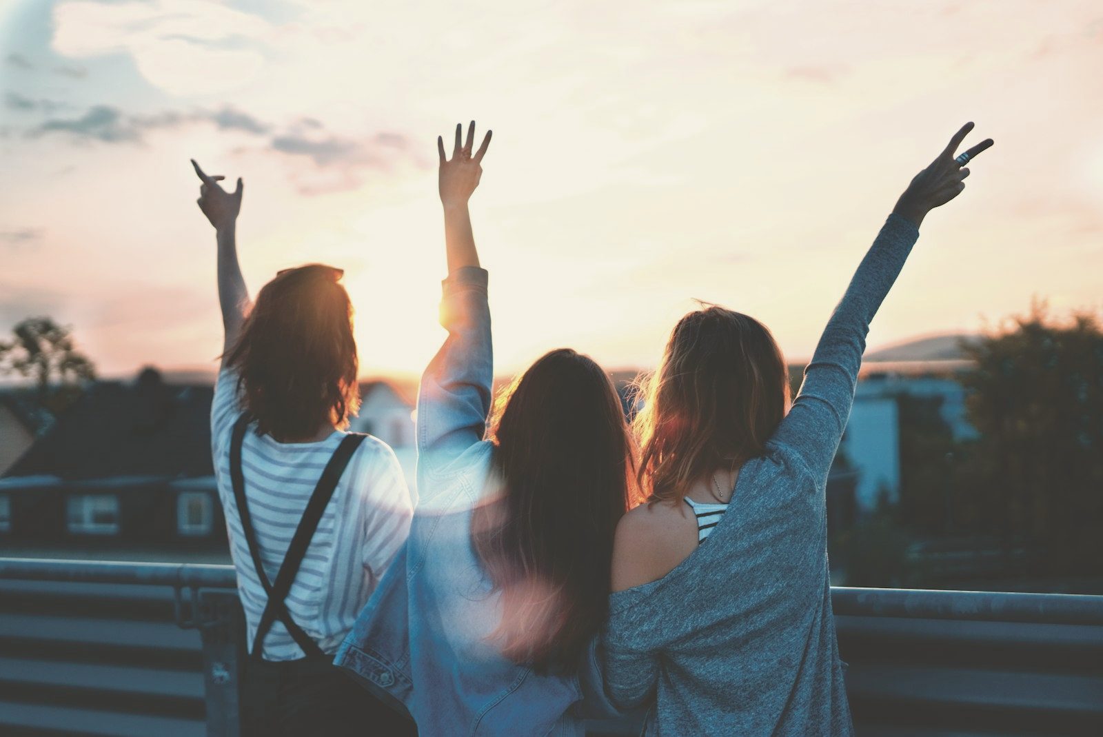 Three people photographed from behind with their arms raised at a gathering