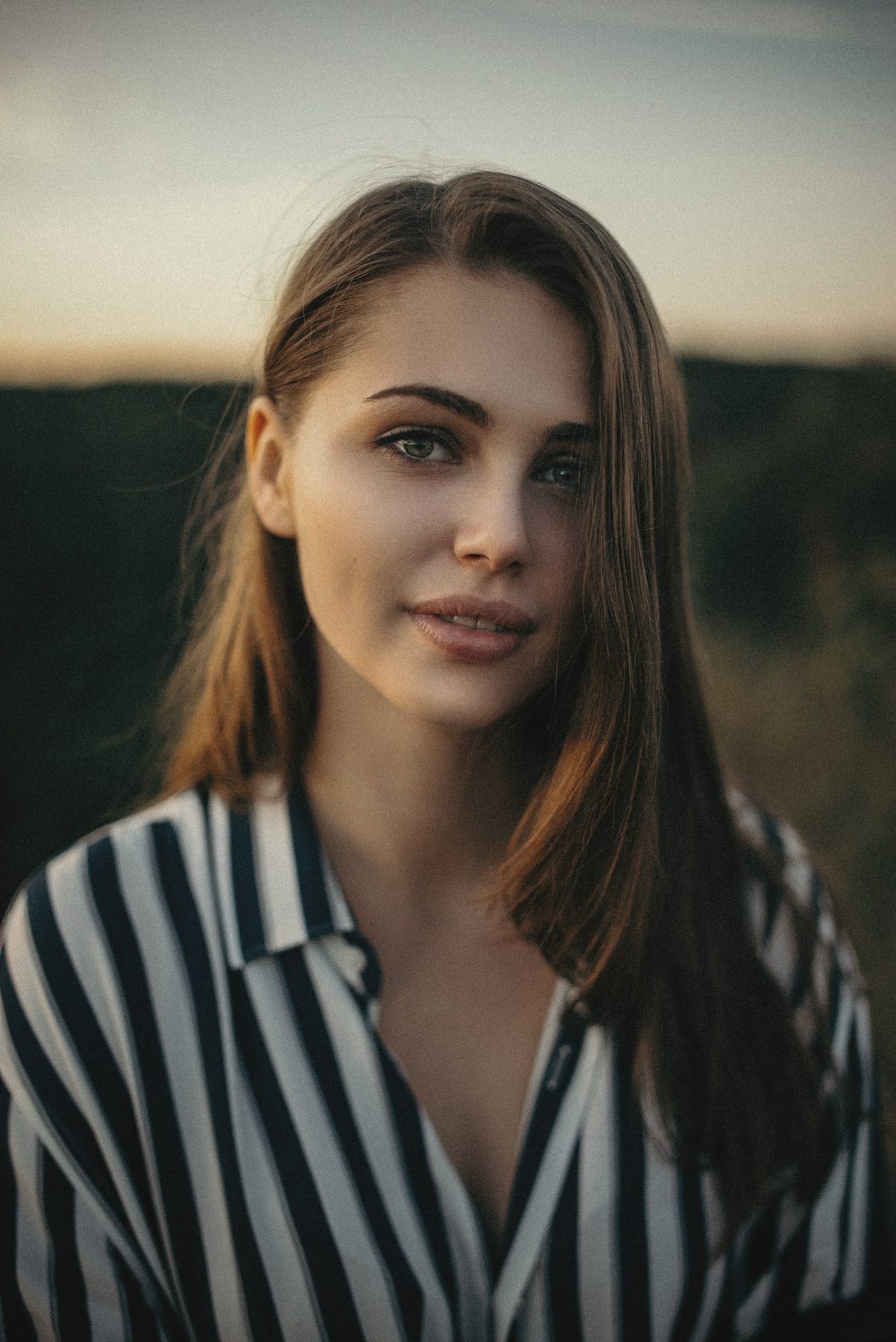 A young woman in a striped shirt against a dark background